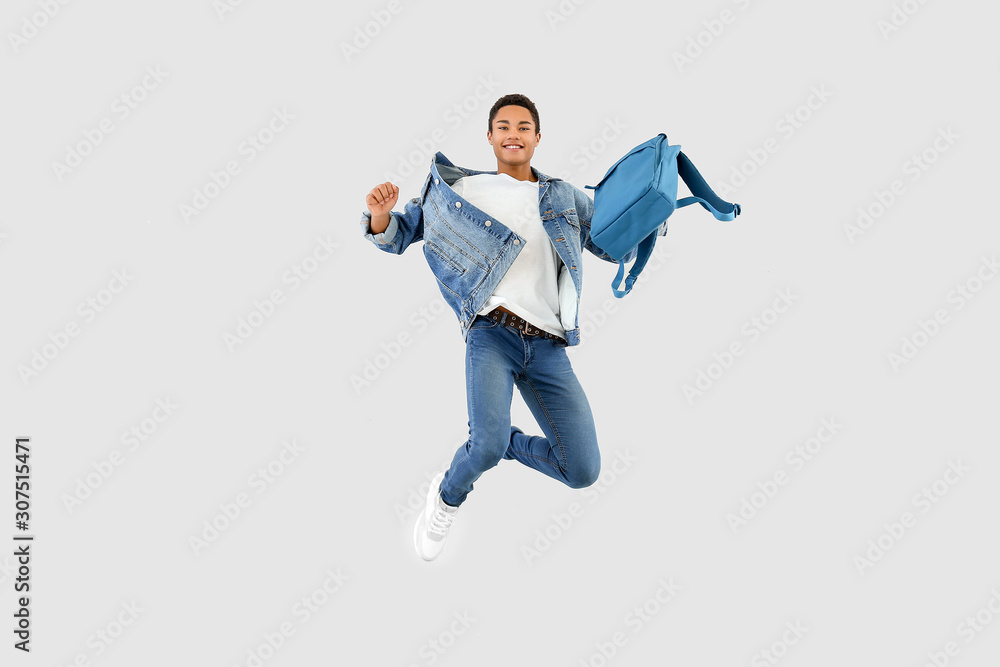 Obraz Jumping African-American teenager boy with backpack on white background fototapeta, plakat