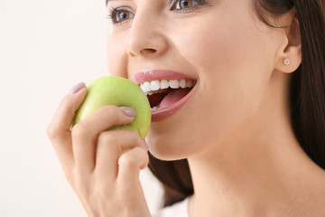 Poster - Beautiful young woman with fresh apple on light background