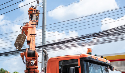 Two electrician workers are climbing on the electric poles to install and repair power lines.