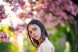 © Volodymyr - Spring girl face. Close up portrait of tender woman at sakura flowers background. Hanami celebration in sakura blooming garden. Young stylish woman walking in sakura park and enjoy beauty of pink
