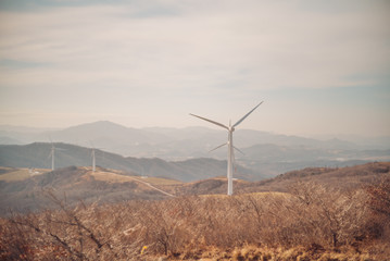 Wind power generator on the summit of mountains with cloudy sky. 