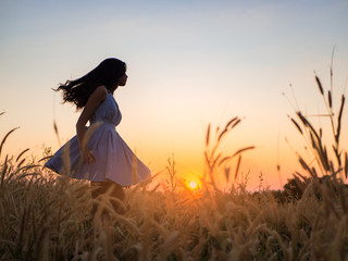 Wall Mural - Trendy girl in stylish summer dress feeling free in the field with flowers in sunshine.