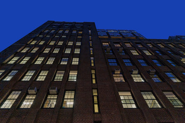 Looking up at a facade of a tall brick building on Manhattan's Upper East Side at night, New York City