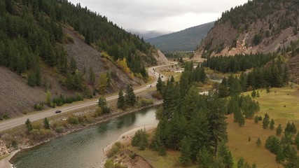 Wall Mural - Road along River through Mountains (drone video)