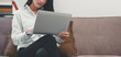 © Joke Phatrapong - Cropped photo of Confident young woman in smart casual wear working on laptop while sitting sofa in creative office. Happy female watching tutorial about creative ideas,reading business news on laptop