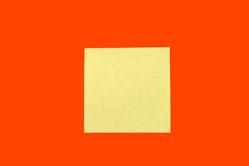 Wall Mural - Yellow sticker note on a bright orange red. Business background, copy space