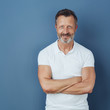 © contrastwerkstatt - Smiling middle-aged man with arms folded