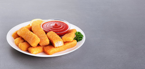 Wall Mural - Fish fingers sticks on a plate with parsley, lemon and ketchup on a gray texture.