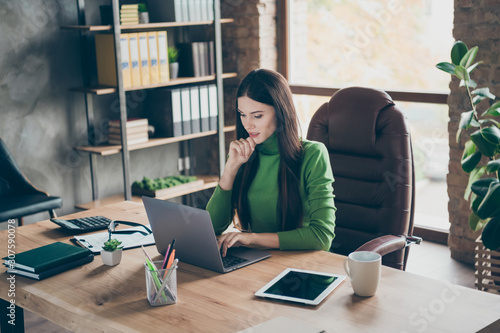 Profile photo of pretty young business lady looking seriously screen notebook on table modern user typing corporate answer sitting boss chair wear green turtleneck modern interior office