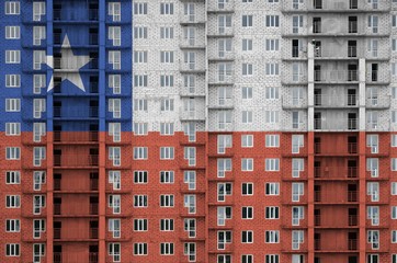 Chile flag depicted in paint colors on multi-storey residental building under construction. Textured banner on brick wall background