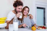 Fototapeta Panele - happy young couple have fun in modern kitchen indoor while preparing fresh fruits and vegetables food salad. Beautiful young couple talking and smiling while cooking healthy food in kitchen at home.