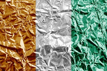 Wall Mural - Ivory Coast flag depicted in paint colors on shiny crumpled aluminium foil closeup. Textured banner on rough background