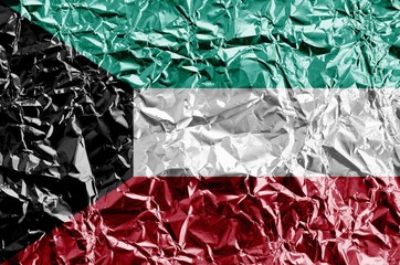 Wall Mural - Kuwait flag depicted in paint colors on shiny crumpled aluminium foil closeup. Textured banner on rough background