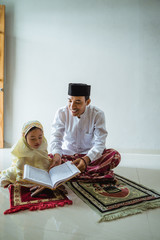 Wall Mural - muslim father and daughter pray together sitting on the floor