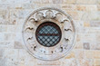 © Shi  - Round window with a black metal fence in an old brick and stone facade
