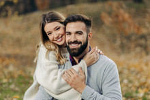 Young Loving Couple Enjoying Embraced In Autumn Day And Looking At Camera