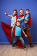 © Sergey Mironov - Young parents and children superheroes in red cloaks on blank blue background