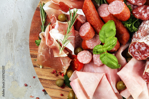 Cuadros en Lienzo Food tray with delicious salami, pieces of sliced prosciutto crudo, sausage and basil