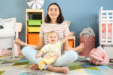 Wall Mural - Young mother with little baby meditating at home