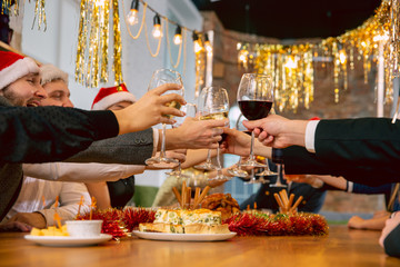 Wall Mural - Happy co-workers celebrating while company New Year and Christmas party. Young caucasian people in celebrate attire talk, drink wine, cheers. Concept of office culture, teamwork, friendship, winter.