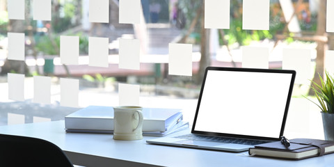 Workspace desk with Mockup Laptop with blank screen and coffee mug, notebook with document paper in office table.