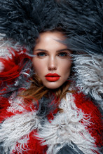 Beautiful Woman With Classic Holiday Make-up, Red Lips, Curls In A Multi-colored Llama Coat. Beauty Face.