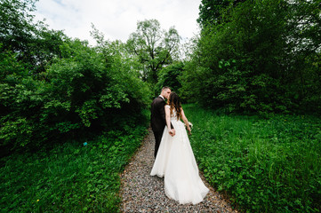  Attractive couple newlyweds on track in the garden. Outdoors. Romantic wedding moment.