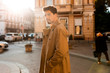© Anton - Young handsome casual man in trench coat confidently looking away walking through street
