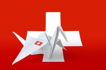 switzerland flag depicted on paper origami crane wing. handmade arts concept