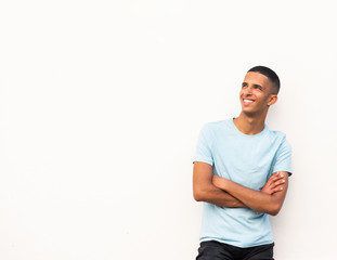 Wall Mural - smiling young North African man with arms crossed and looking away by white background