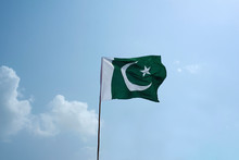 The National Flag Of Pakistan Flying In The Blue Sky With Clouds