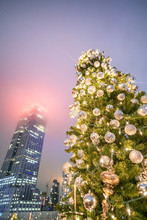 Christmas Tree With Tall Skyscrapers At Night In Background. Holiday And Business Concept