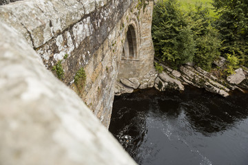 A medieval stone brickwork bridge. historic landmark. people jump from this bridge for fun and recreation. a bridge with history.