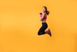© ClaudiK - Inspired woman training in headphones. Slim caucasian girl doing excersizes.Woman in sportswear running over yellowbackground. Full length shot of healthy young caucasian woman sprinting. Copy space.