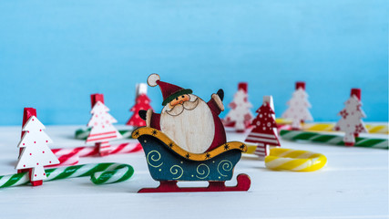 Wall Mural - Miniature Santa Claus, Christmas trees and candies on blue background. Copy space.