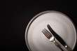 © Тимур Конев - Closeup empty round gray ceramic plate on black background, vintage cupronickel fork, knife with copy space. Concept modern shooting menu from chef, restaurant advert, tableware catalog, top view