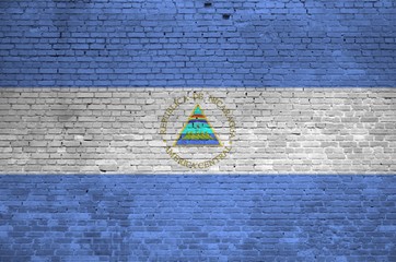 Nicaragua flag depicted in paint colors on old brick wall. Textured banner on big brick wall masonry background