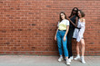 © Vasya - Full length stylish portrait of the young beautiful multi ethnic girls in casual clothes isolated over red brick wall