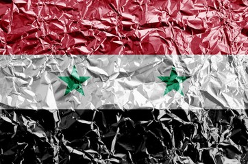 Syria flag depicted in paint colors on shiny crumpled aluminium foil closeup. Textured banner on rough background