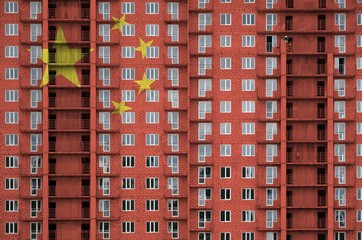 China flag depicted in paint colors on multi-storey residental building under construction. Textured banner on brick wall background