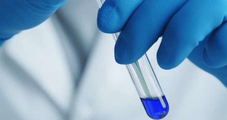 Wall Mural - close-up shot with hitting laboratory equipment. blue liquid falling pipette in glass test tube.