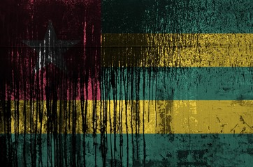 Wall Mural - Togo flag depicted in paint colors on old and dirty oil barrel wall closeup. Textured banner on rough background