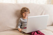 © selugallego - Child sitting on a sofa watching a laptop.