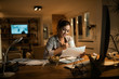 © Drazen - Smiling woman drinking tea while learning in the evening at home.
