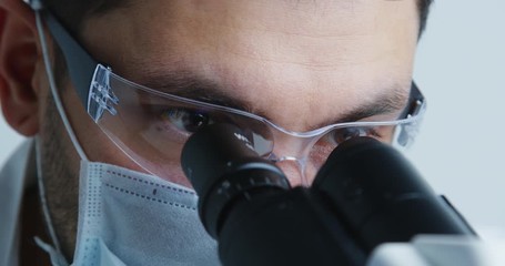 Wall Mural - young scientist looks under microscope in the laboratory.
