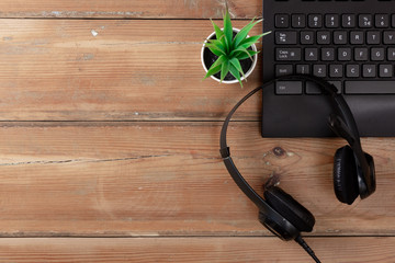 Keyboard a plants and earphones on a wooden background with microphone with copy space