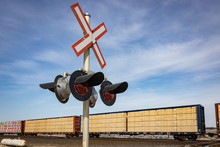 Railway Crossing Sign In Front Of Freight Train Carrying Lumber