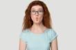 Funny red-haired woman making fish kisses with face.