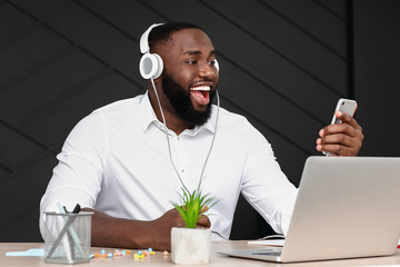 Wall Mural - African-American man listening to music in office