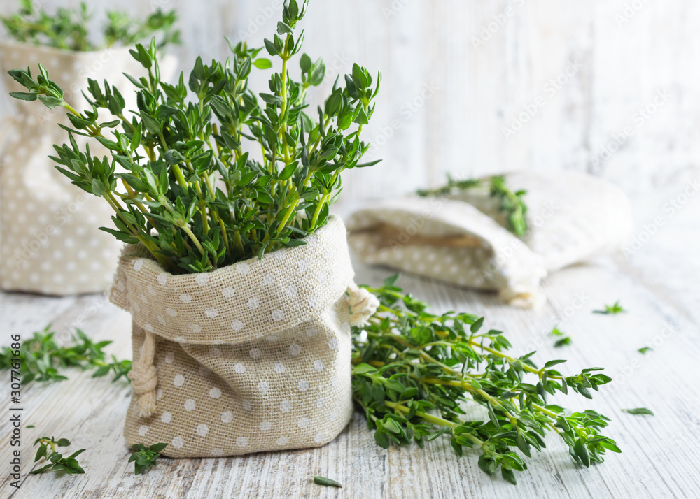 Fresh green thyme in decorative linen bag on an old wooden table. - obrazy, fototapety, plakaty 